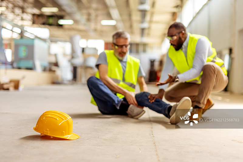 在建筑工地上，受伤的工人得到同事的帮助图片素材