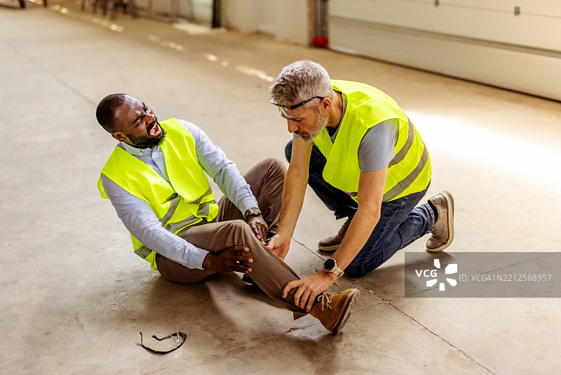 工人在工地上帮助受伤的同事，穿着高可视性背心图片素材