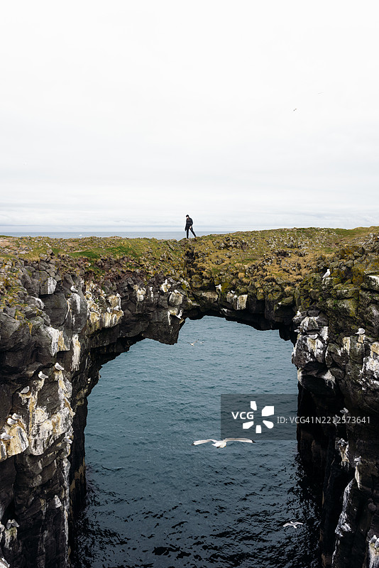 旅客在风景如画的自然拱门上俯瞰壮丽的北欧自然景观图片素材