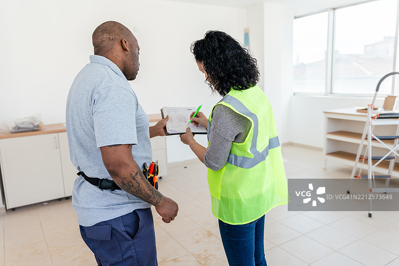 建筑工人在新厨房内审查翻新计划图片素材