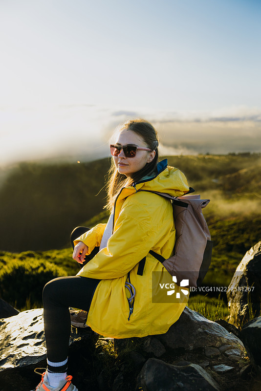 戴着太阳镜的快乐女性与马德拉山脉上空的戏剧性日出相遇图片素材