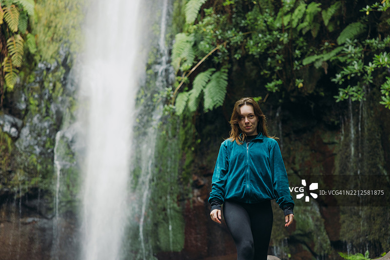 年轻迷人的女性在丛林中探寻壮丽的瀑布图片素材