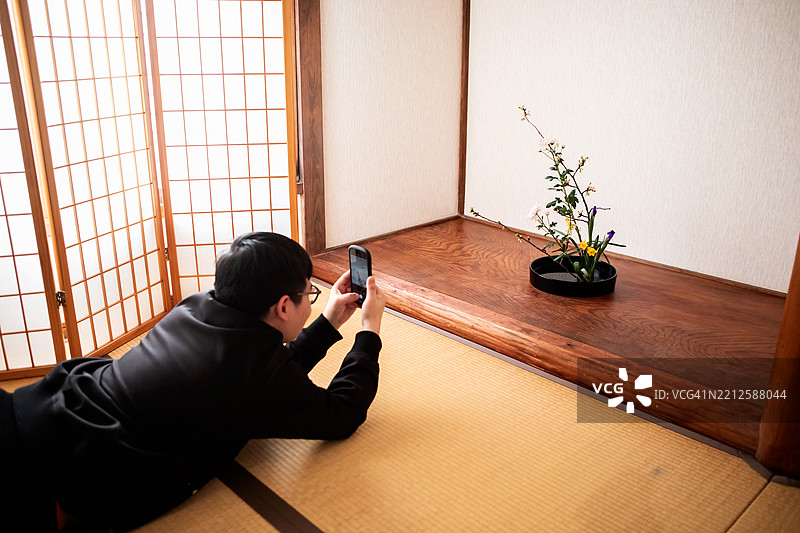 一名印尼男子正在花艺工作坊上拍摄作品。图片素材