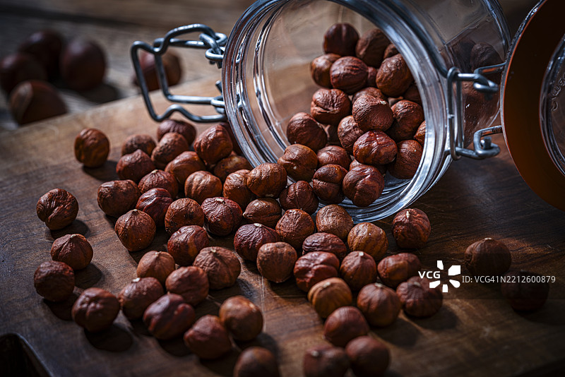 剥皮有机榛子从罐子里倒出，放在乡村风格的桌子上图片素材