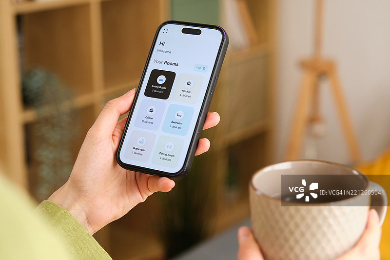 女性在享受咖啡时，通过手机应用管理智能家居设备图片素材