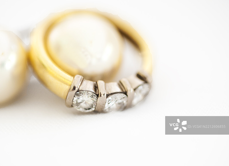 一枚镶有三颗钻石和珍珠的钻戒。白色背景。特写镜头。图片素材