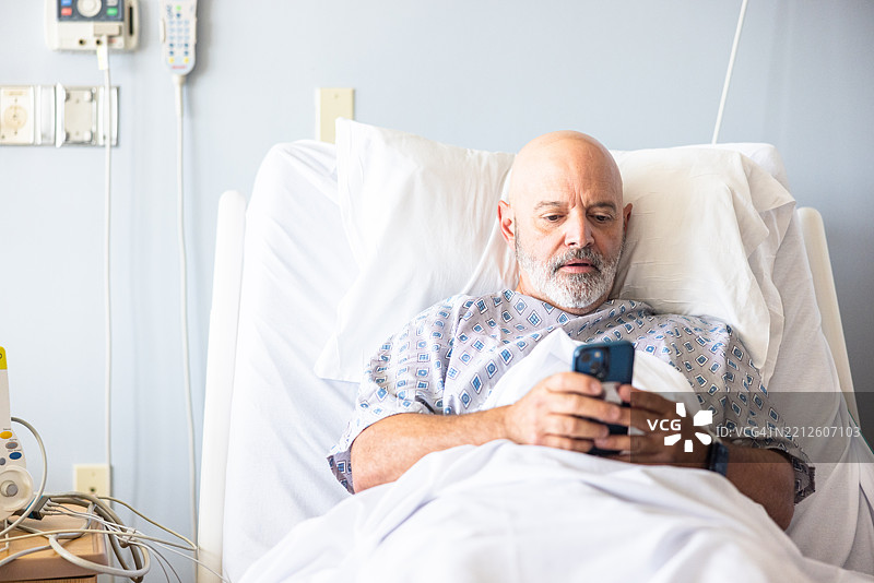 老年男子在医院病床上穿着病号服与医生会面图片素材