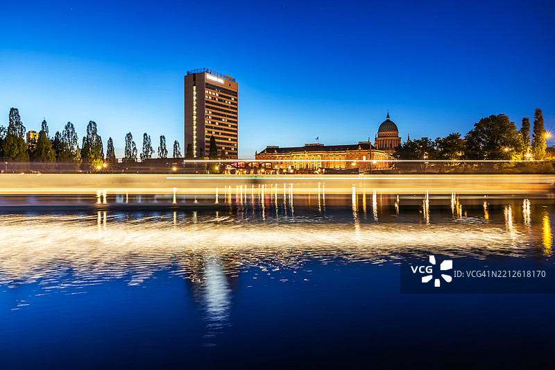 波茨坦城市天际线在蓝色时刻，快速经过的游船 - 酒店摩天大楼、城市宫殿和圣尼古拉教堂图片素材