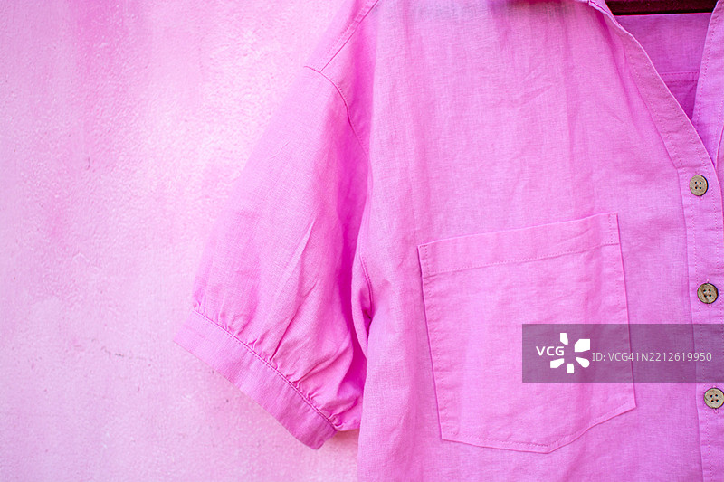 粉色亚麻衬衫挂在粉色墙壁上，时尚与风格图片素材