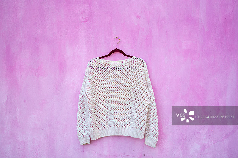空白的白色毛衣挂在粉色墙壁上图片素材