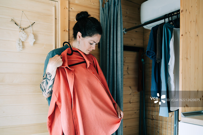 女人在木质小屋的衣橱中挑选衣服图片素材