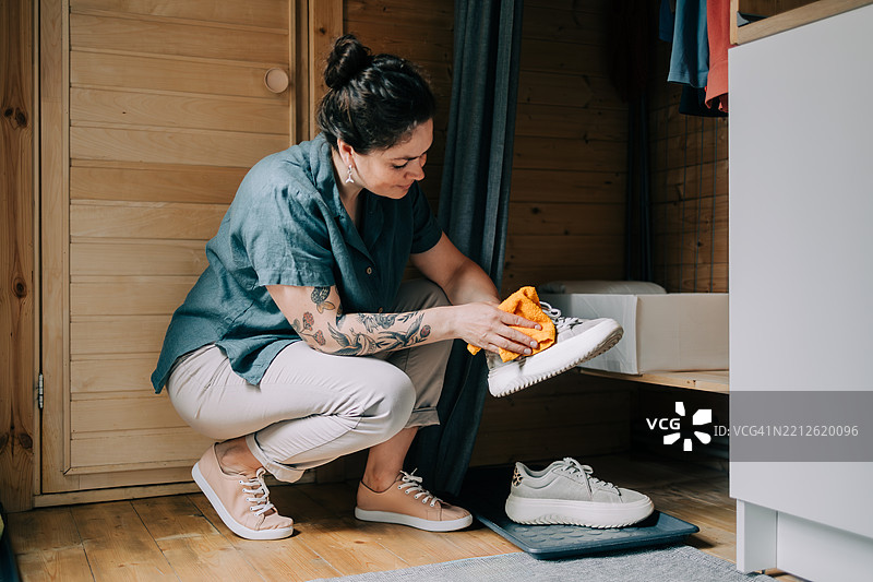 女人在木质衣柜中清洁白色运动鞋图片素材