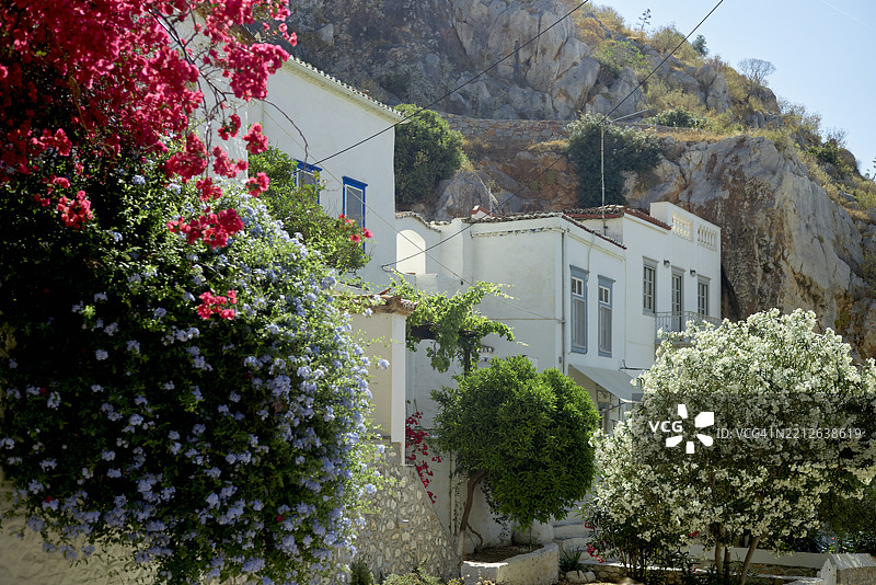 迷人的山坡村庄，鲜艳的花朵和如画的白色建筑。希腊，海德拉岛图片素材
