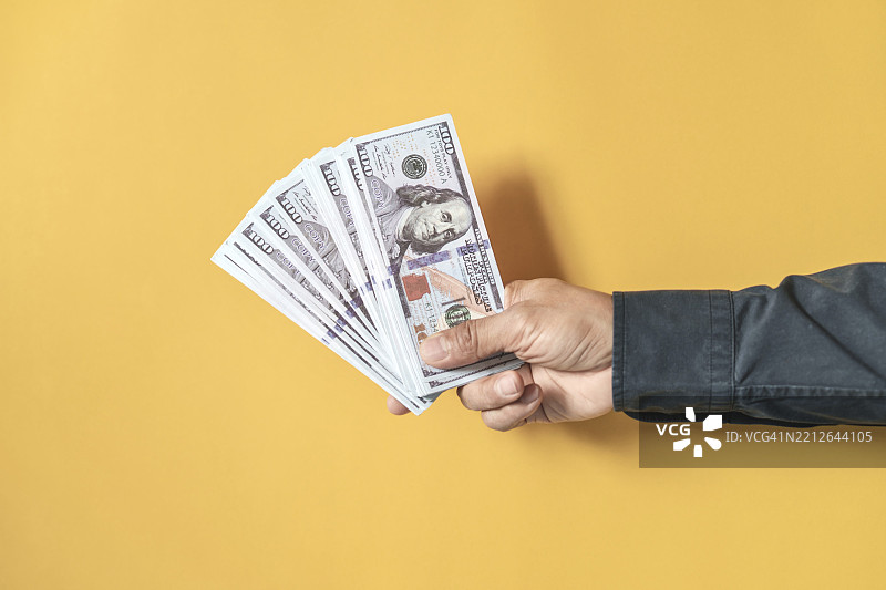 商人手中握着美元钞票，留有空白空间。图片素材