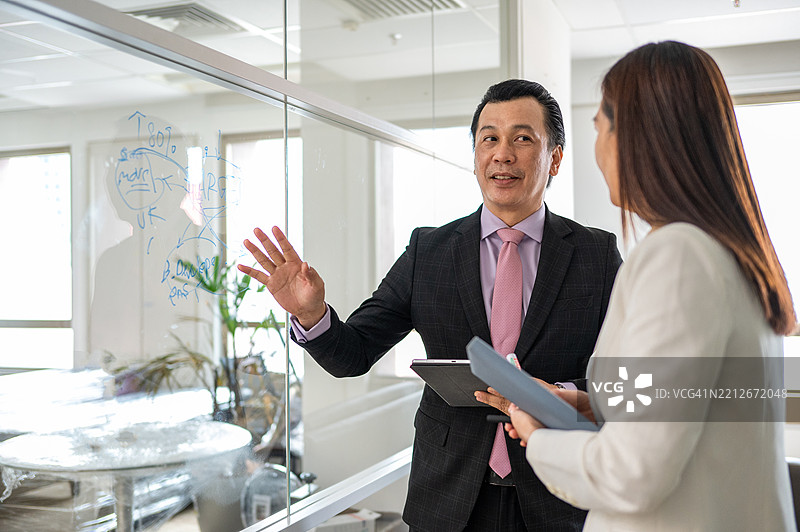 亚洲商人与女性讨论并使用智能平板进行解释的照片图片素材