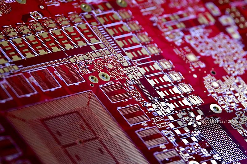 红色电路板上的电气路径，清晰可见的电阻器和芯片。图片素材