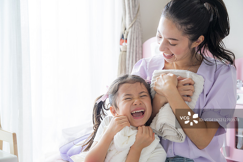 母女在阳光明媚的卧室里用毛巾欢笑图片素材