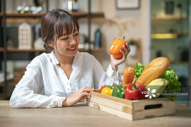 女人微笑着挑选木篮中的新鲜蔬菜图片素材