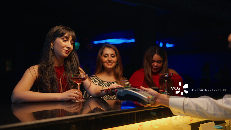 女性在酒吧用手机进行无接触支付图片素材