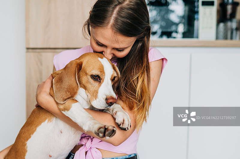 女人在温暖而充满爱的场景中拥抱一只比格犬图片素材