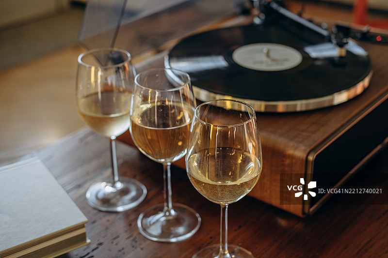 在家与朋友聚会，享受白葡萄酒和黑胶唱片音乐图片素材