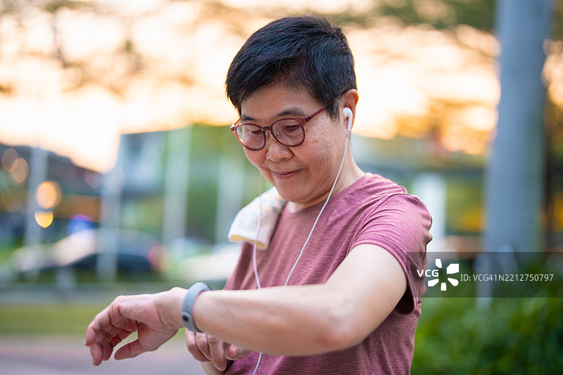 一位老年女性在公共公园锻炼后佩戴着智能手表。图片素材