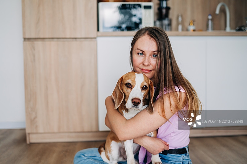 女人在温暖而充满爱的场景中拥抱一只比格犬图片素材