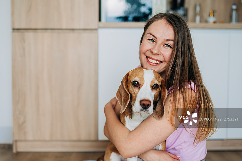 女人在温暖而充满爱的场景中拥抱一只比格犬图片素材