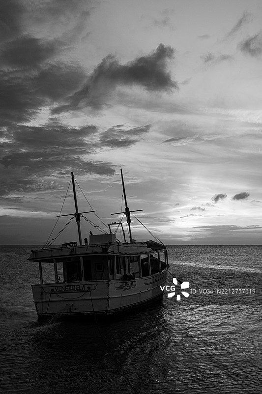 码头的黄金时刻：木质渔船在充满活力的加勒比海日落下的剪影。图片素材