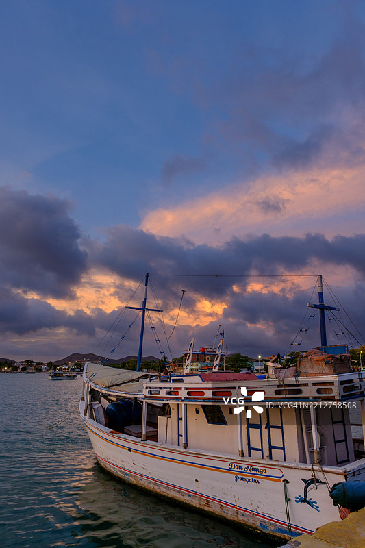 码头的黄金时刻：木质渔船在充满活力的加勒比海日落下的剪影。图片素材