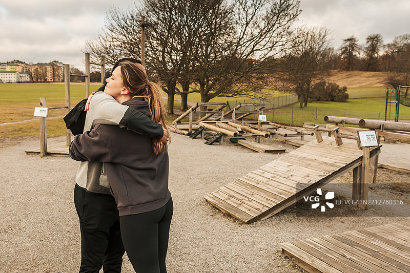 一对年轻情侣在户外健身房相遇时互相拥抱。图片素材