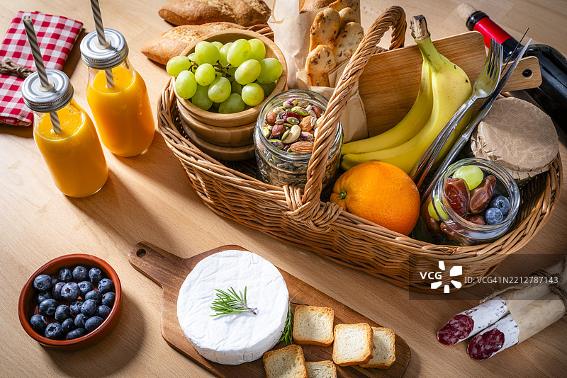 高角度视图的藤编篮子放在野餐桌上，里面装满了美味的食物和饮料图片素材