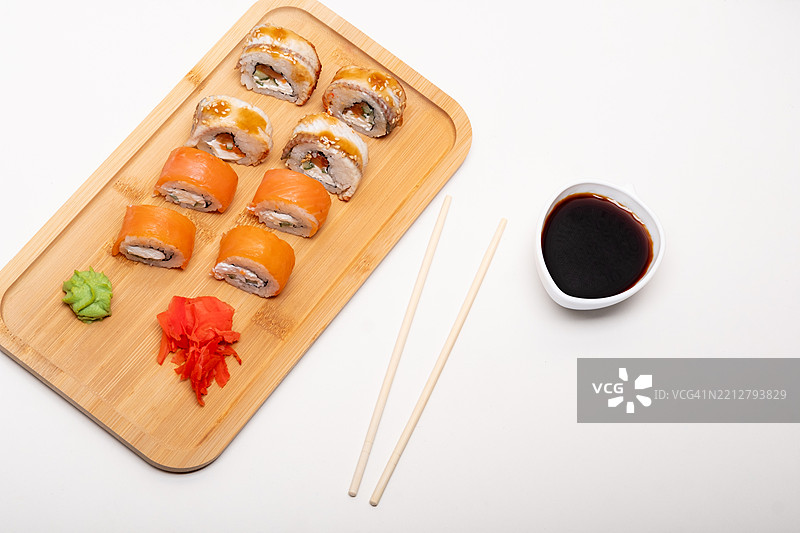 木托盘上的米饭和鱼卷，配有酱油、芥末和姜。图片素材