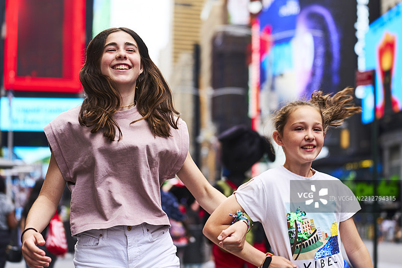 两个快乐的女孩在纽约市时代广场奔跑图片素材
