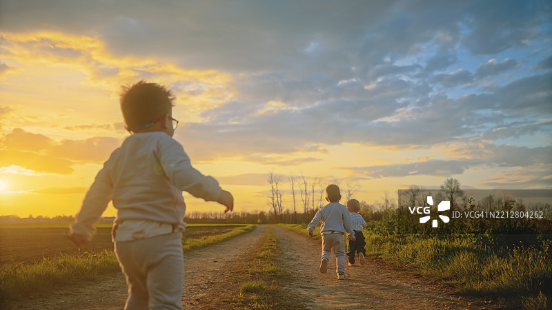 乡村日落时分，孩子们在泥土路上奔跑图片素材