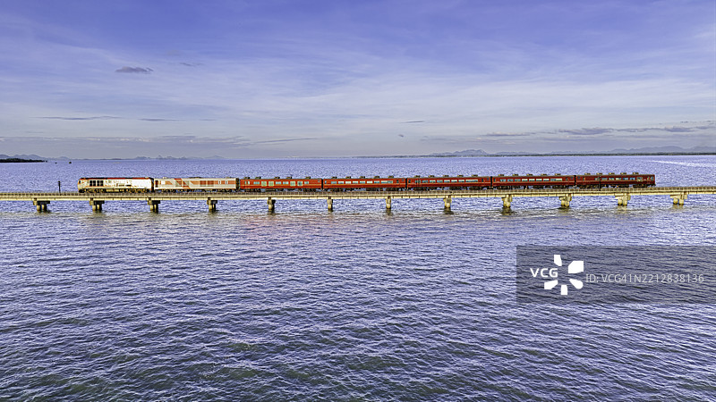 从空中俯瞰，客运列车在穿过大坝的铁路上停靠。图片素材