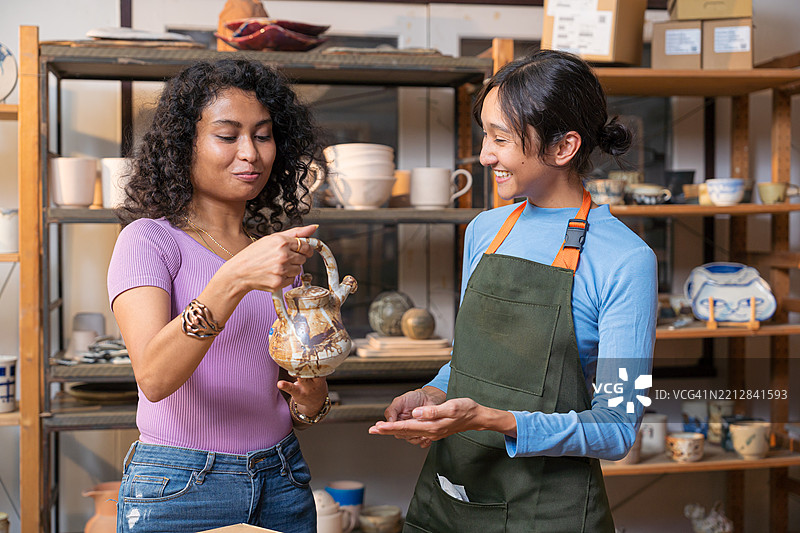 小企业主在陶瓷店向顾客展示她的陶瓷产品。图片素材