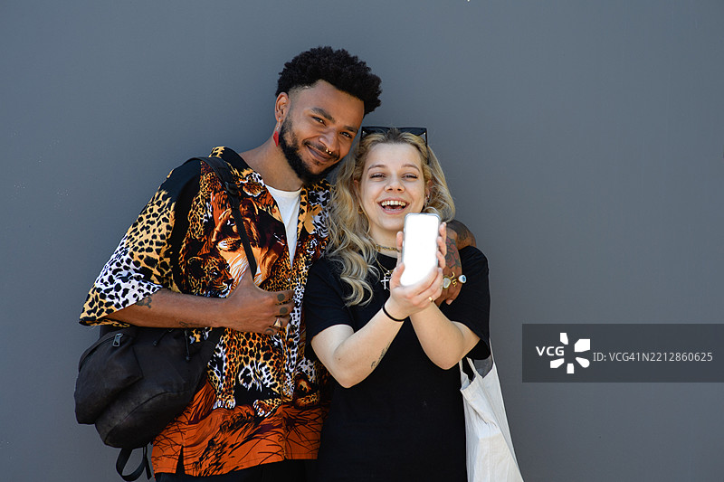 一对年轻的多种族情侣向镜头展示手机的白色屏幕图片素材