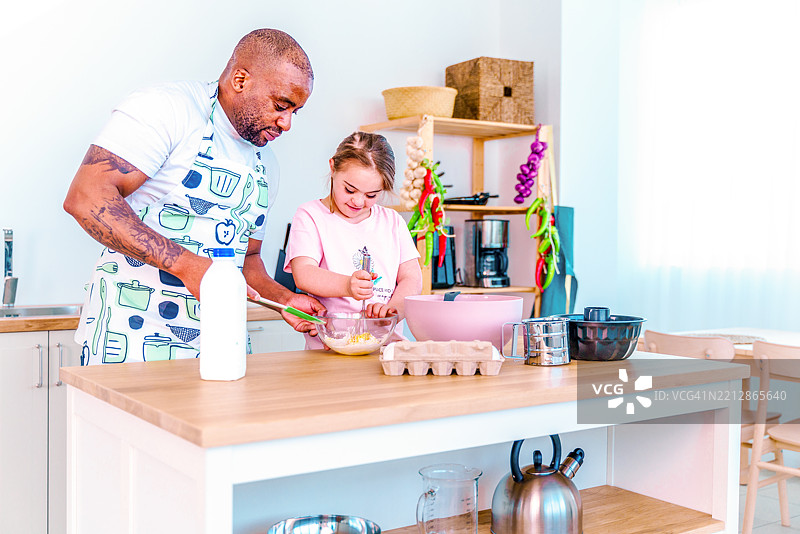 一位黑人父亲和他的养女在厨房里一起快乐地烹饪。图片素材