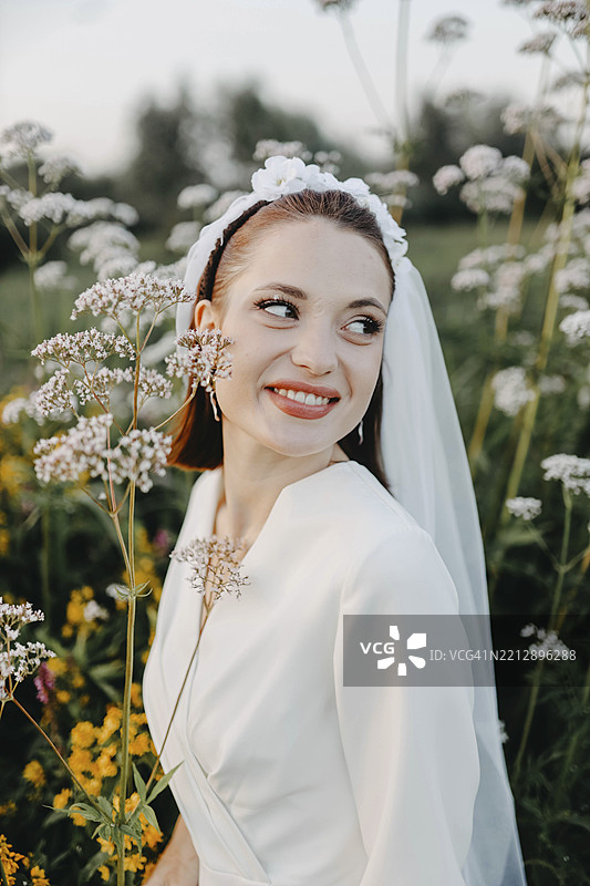 新娘在花田中，灿烂微笑，捕捉到一个快乐而自然的瞬间图片素材