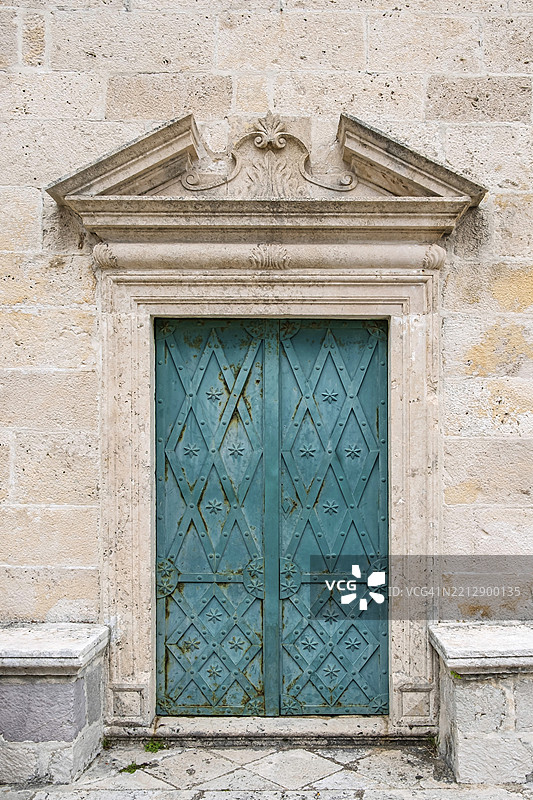 古老的绿色木门，装饰精美，嵌入石墙中，位于黑山的科托尔湾，斯克尔皮耶拉岛，岩石之玛丽，巴尔干半岛，欧洲图片素材