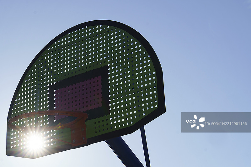 绿色和粉色的篮球架在晴朗的日子里阳光透过。图片素材