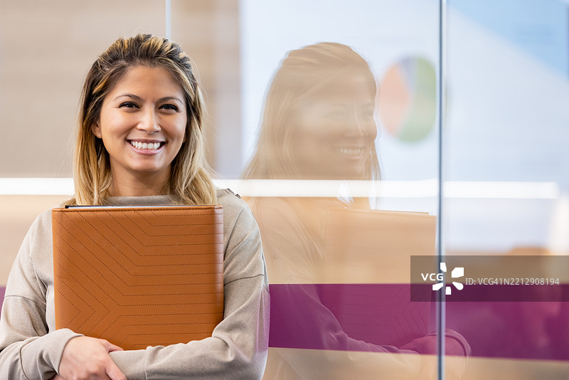 成熟的女商人自信地摆姿势，手持公文包图片素材