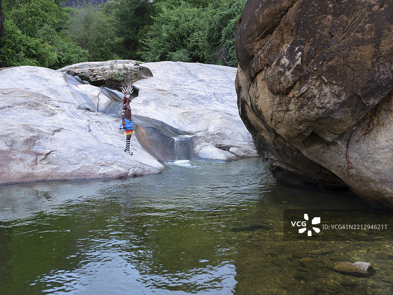 在肯尼亚恩多托的宁静自然风光中，部落的伦迪尔战士站在瀑布旁祈祷。图片素材