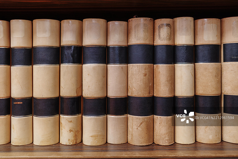 复古的皮革装订法律书籍，棕色和黑色书脊，摆放在木制书架上。图片素材