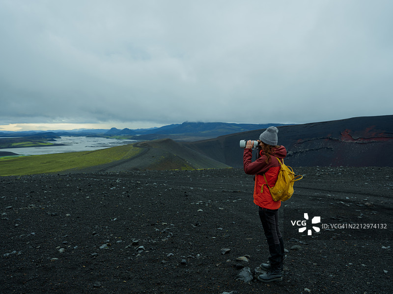 灵感满满的女性手持相机，凝视冰岛的火山湖图片素材