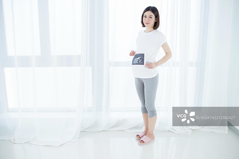 亚洲孕妇手持她的超声波扫描照片图片素材