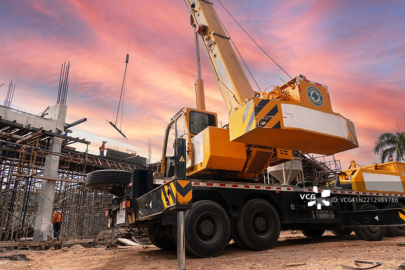 建筑工地上起重机在日落时分吊运材料图片素材