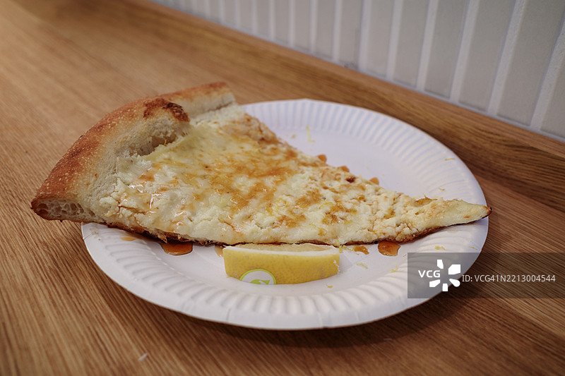 一片厚实松软的白色比萨饼，放在白色纸盘上。图片素材