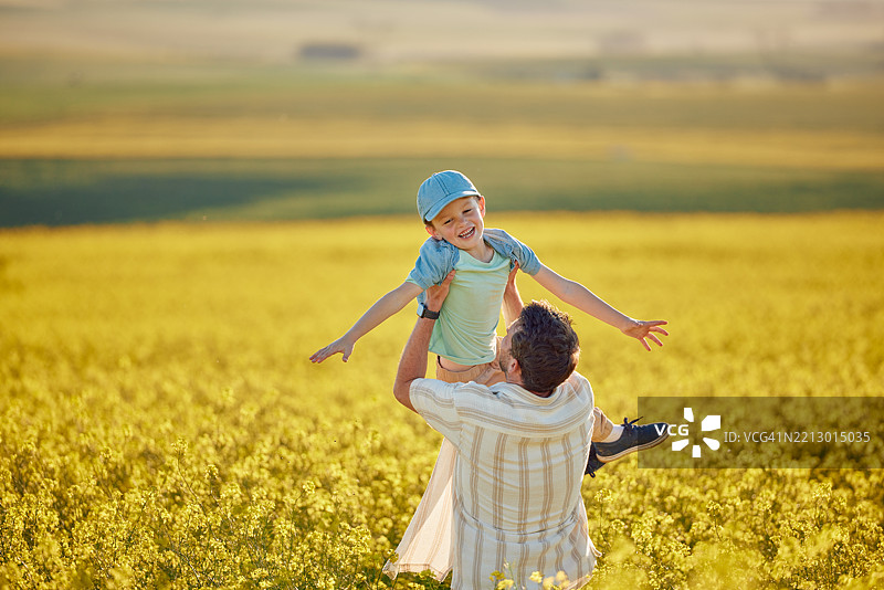 父亲与孩子在乡村度假时在田野中嬉戏，增进亲子关系，享受旅行与冒险。父亲和孩子在大自然中一起玩乐，享受假期、周末旅行的乐趣。图片素材